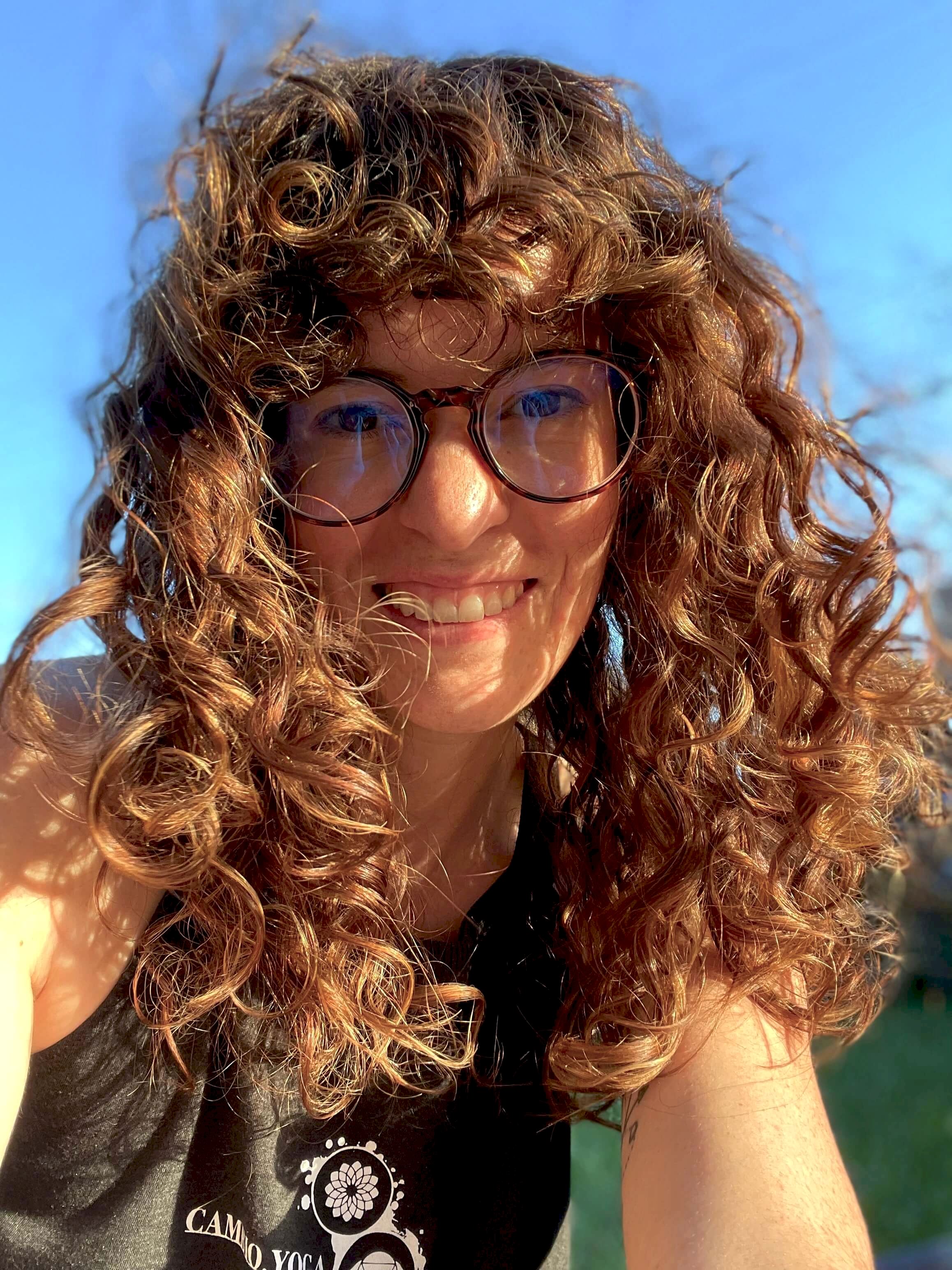 Photo of Erika outside, with her curly hair blowing in her face