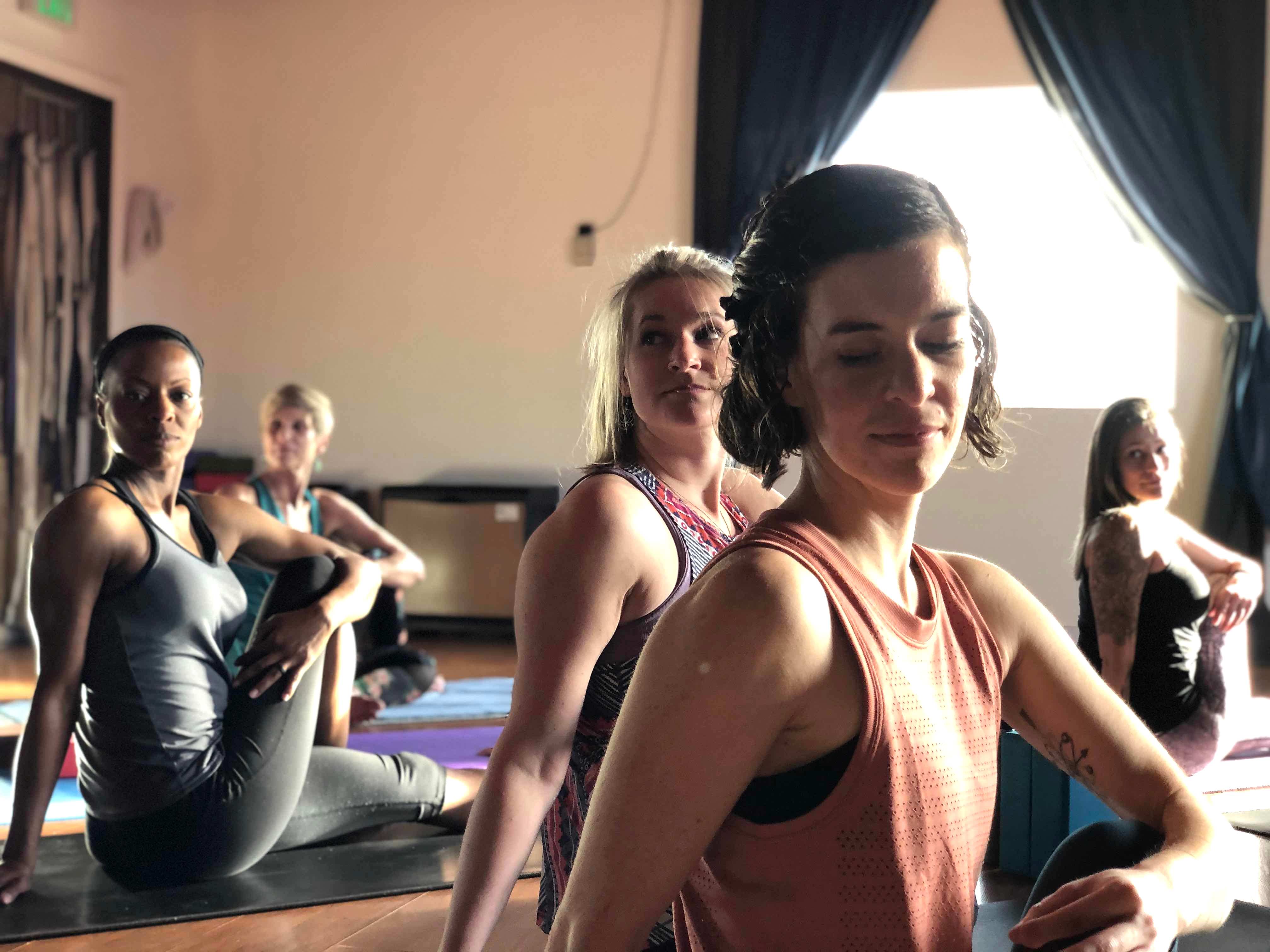Photo of Erika in Ardha Matsyendrāsana with other students behind her