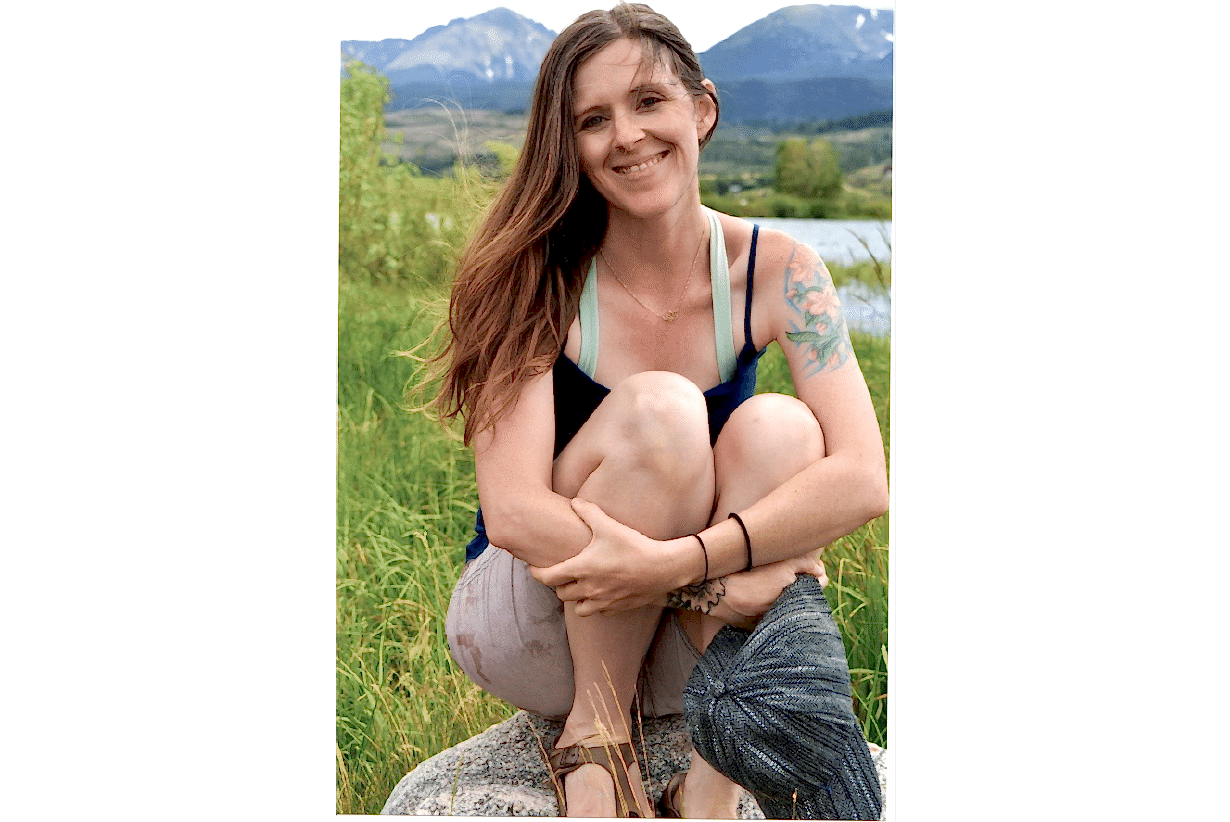 Photo of Alyssa sitting on a rock in the mountains
